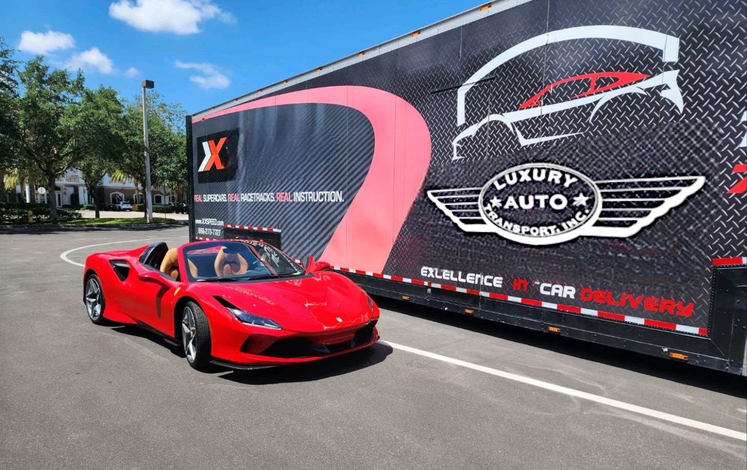 Ferrari parked beside a truck with luxury auto transport branding.