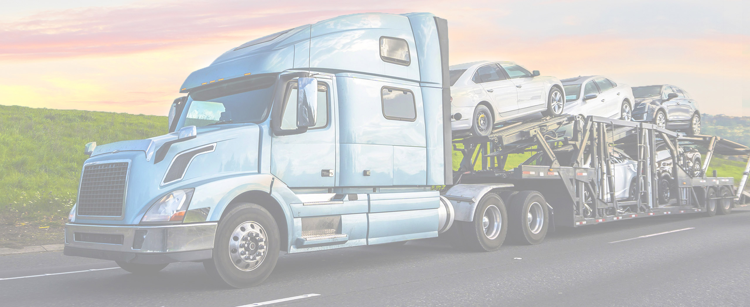 Car carrier transporting vehicles on a highway at dusk.