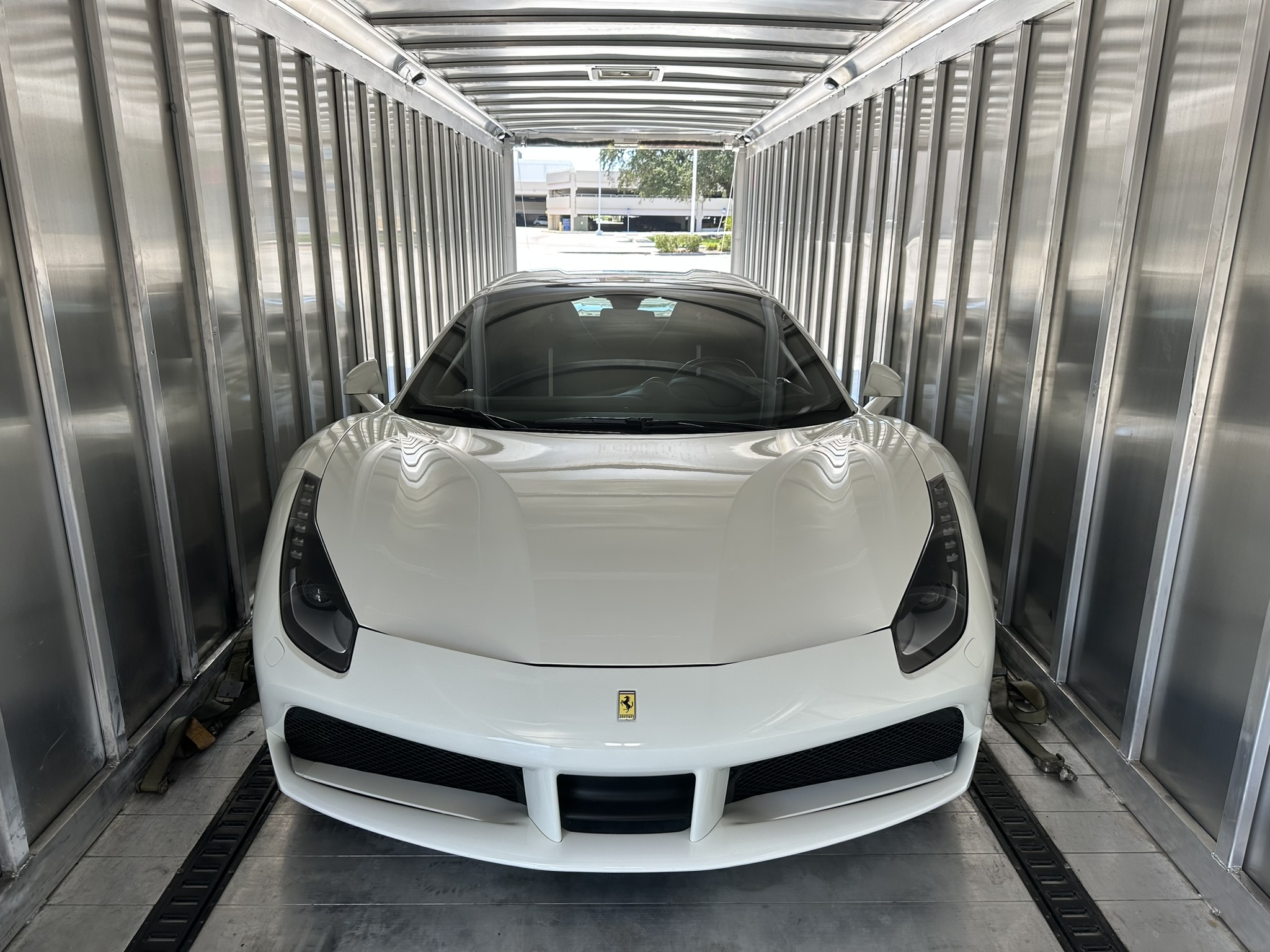 A white sports car parked inside a metal shipping container.