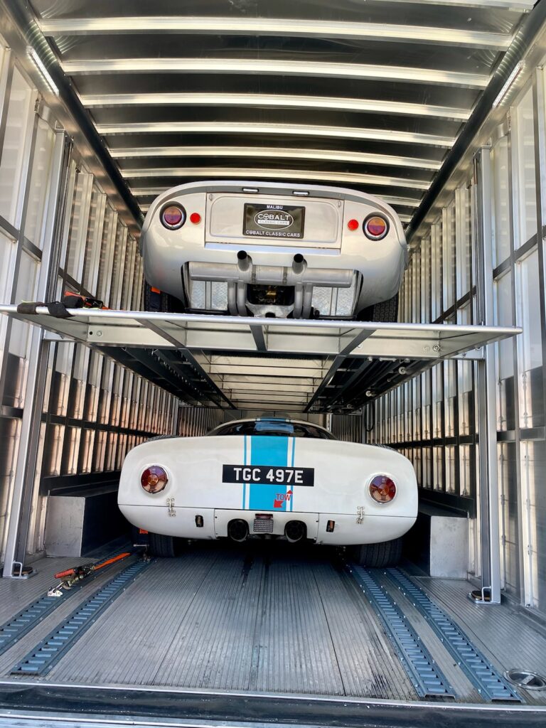 A car positioned in the cargo area of a truck, showcasing the vehicle's secure transport.