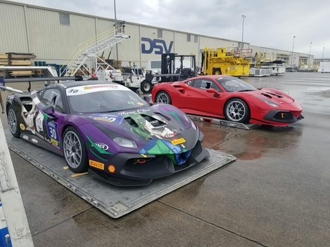 Two Ferrari cars parked on a trailer, showcasing their sleek design and vibrant colors against a clear background.