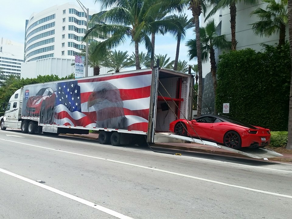 A vibrant red sports car is being loaded onto a truck, ready for transport to its next destination.