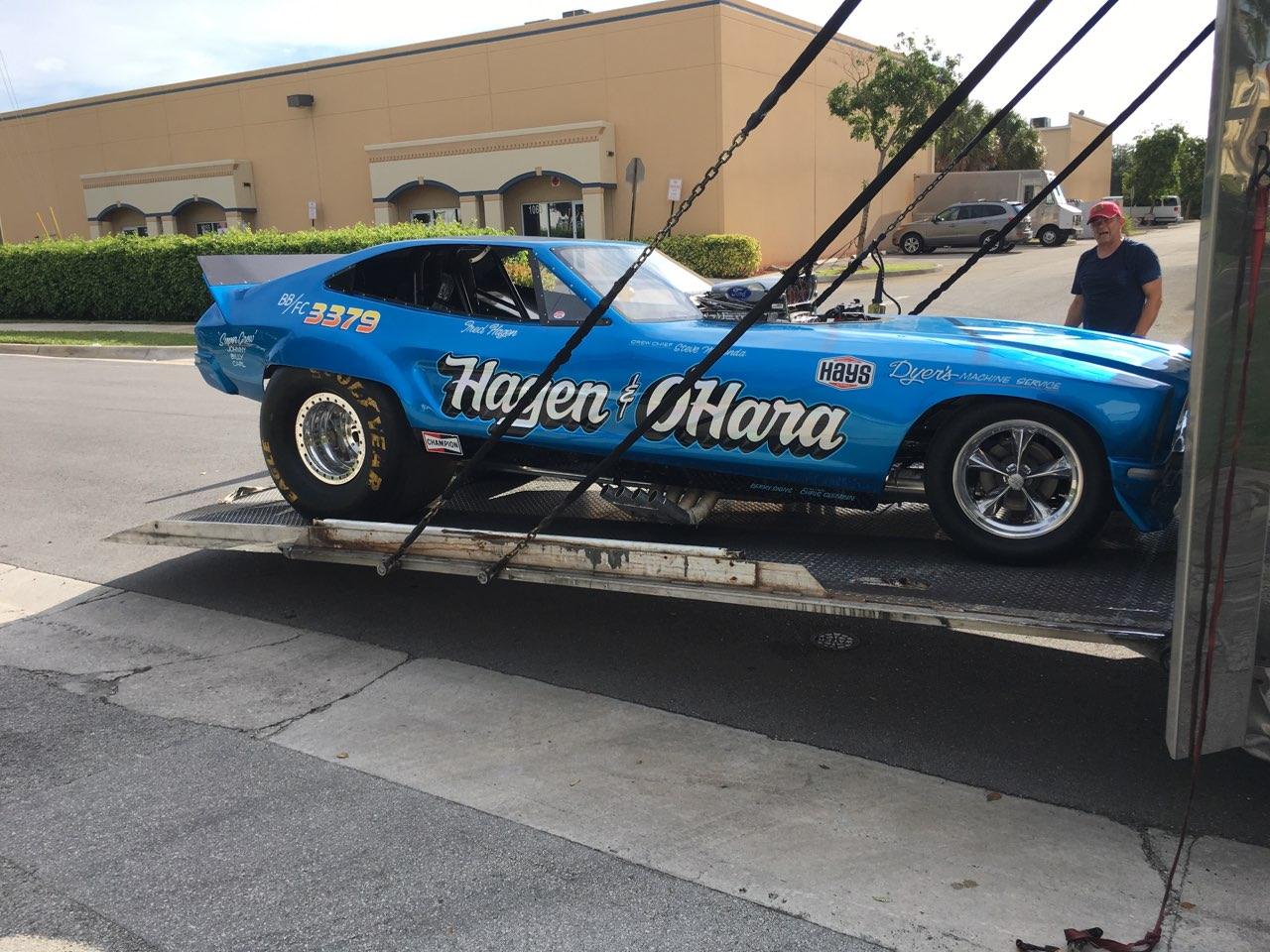 A blue car is securely loaded on a flatbed truck, ready for transport.