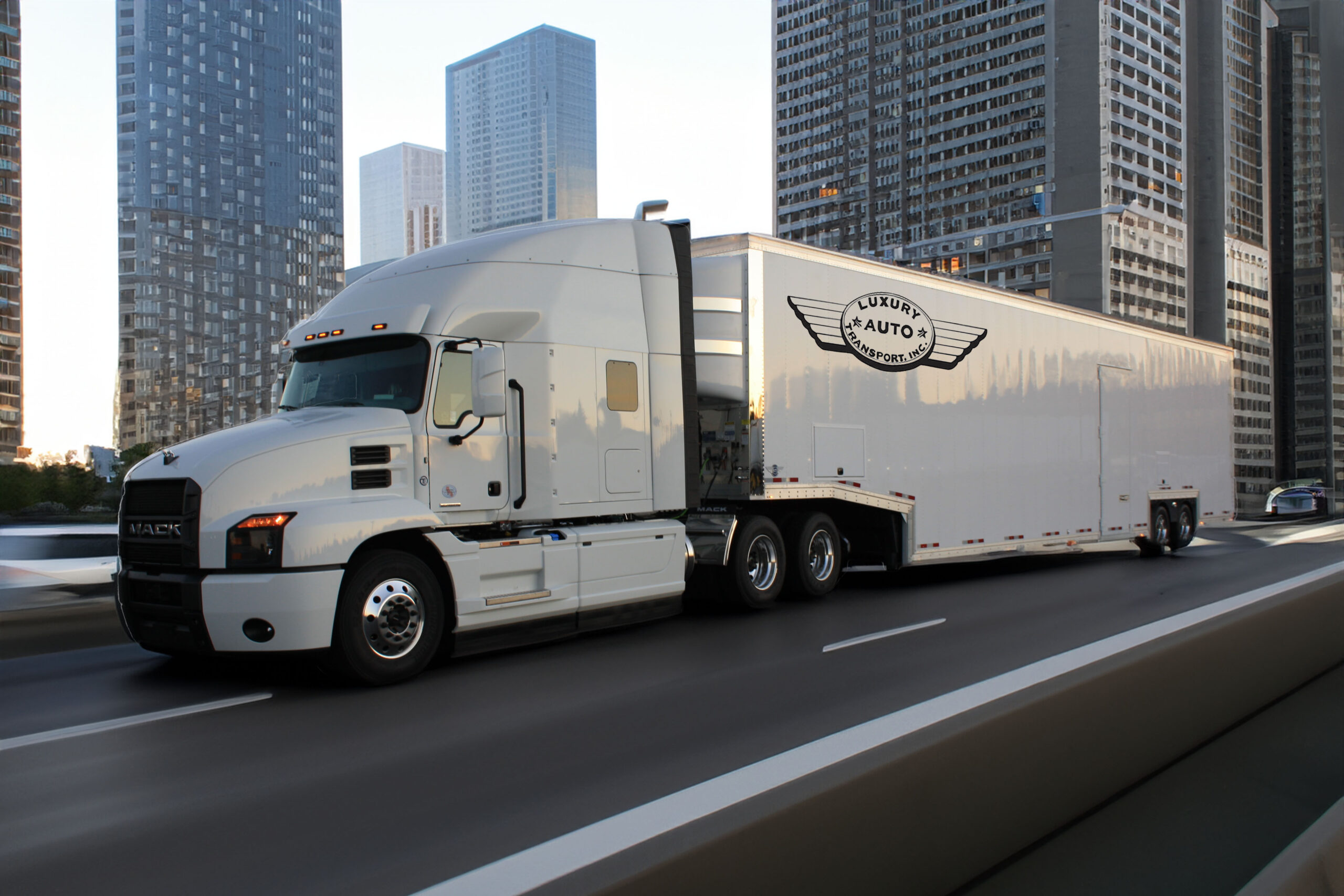 A large white semi-truck, expertly chosen as the best exotic car hauler, drives on a city highway surrounded by skyscrapers. The trailer proudly displays the "Luxury Auto 2" logo, set against an urban backdrop with clear weather.